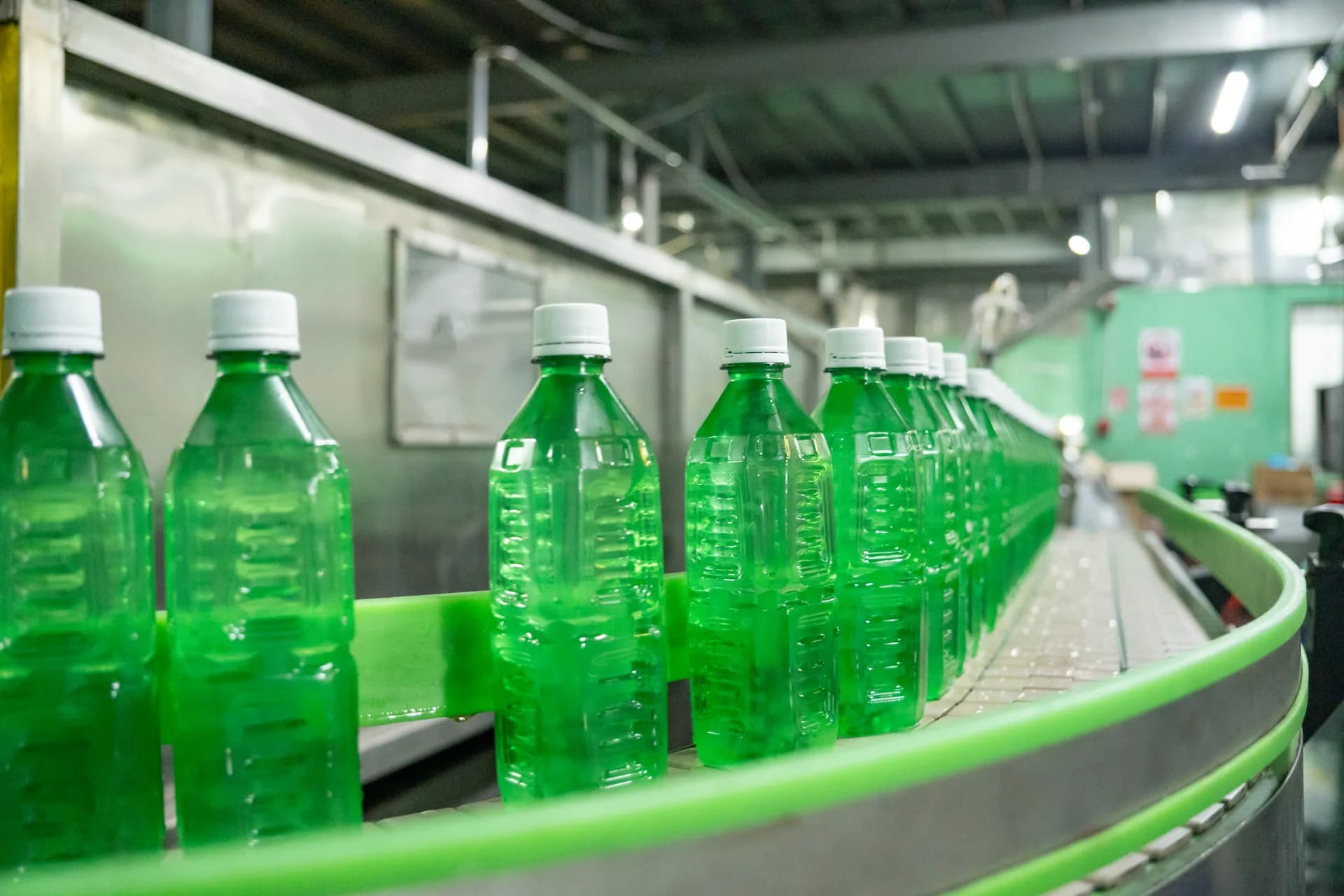 Green beverage bottles moving along a factory conveyor.